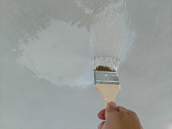 using a chip brush to add texture to a smooth patch on the ceiling.