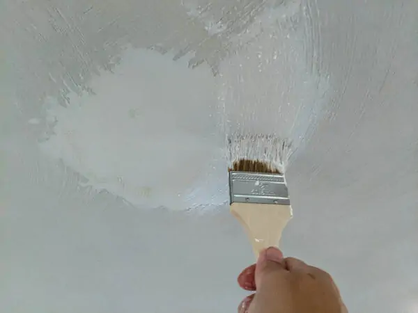 using a chip brush to add texture to a smooth patch on the ceiling.