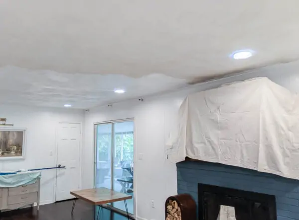 ceiling half painted with fresh white paint and half unpainted.