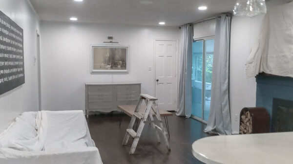 room with couch and tv covered with drop cloth, rug rolled up, and accessories removed.