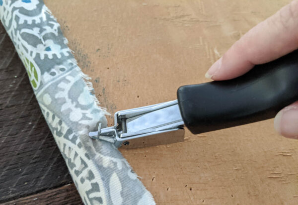 removing the old upholstery using an upholstery staple remover.