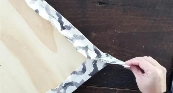 holding fabric at corner of chair seat to create a straight fold.