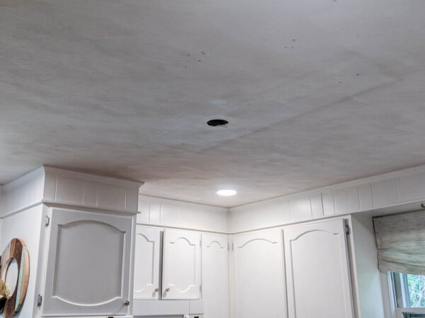 Ceiling in kitchen with big hole, stains, and lots of yellowing.