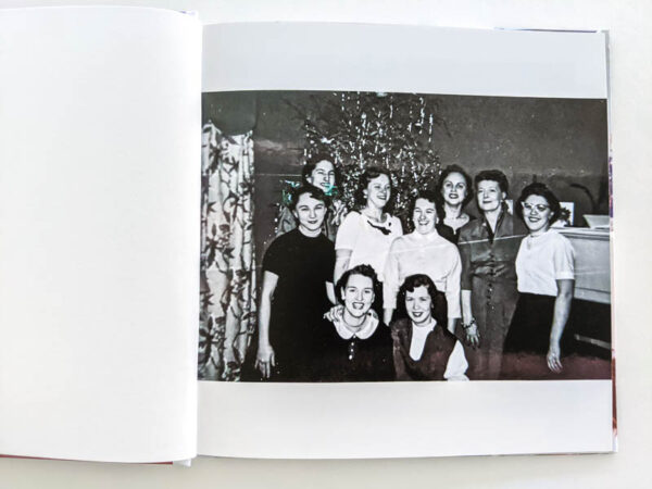 Christmas photo book open to black and white picture of group of ladies in front of a Christmas tree.