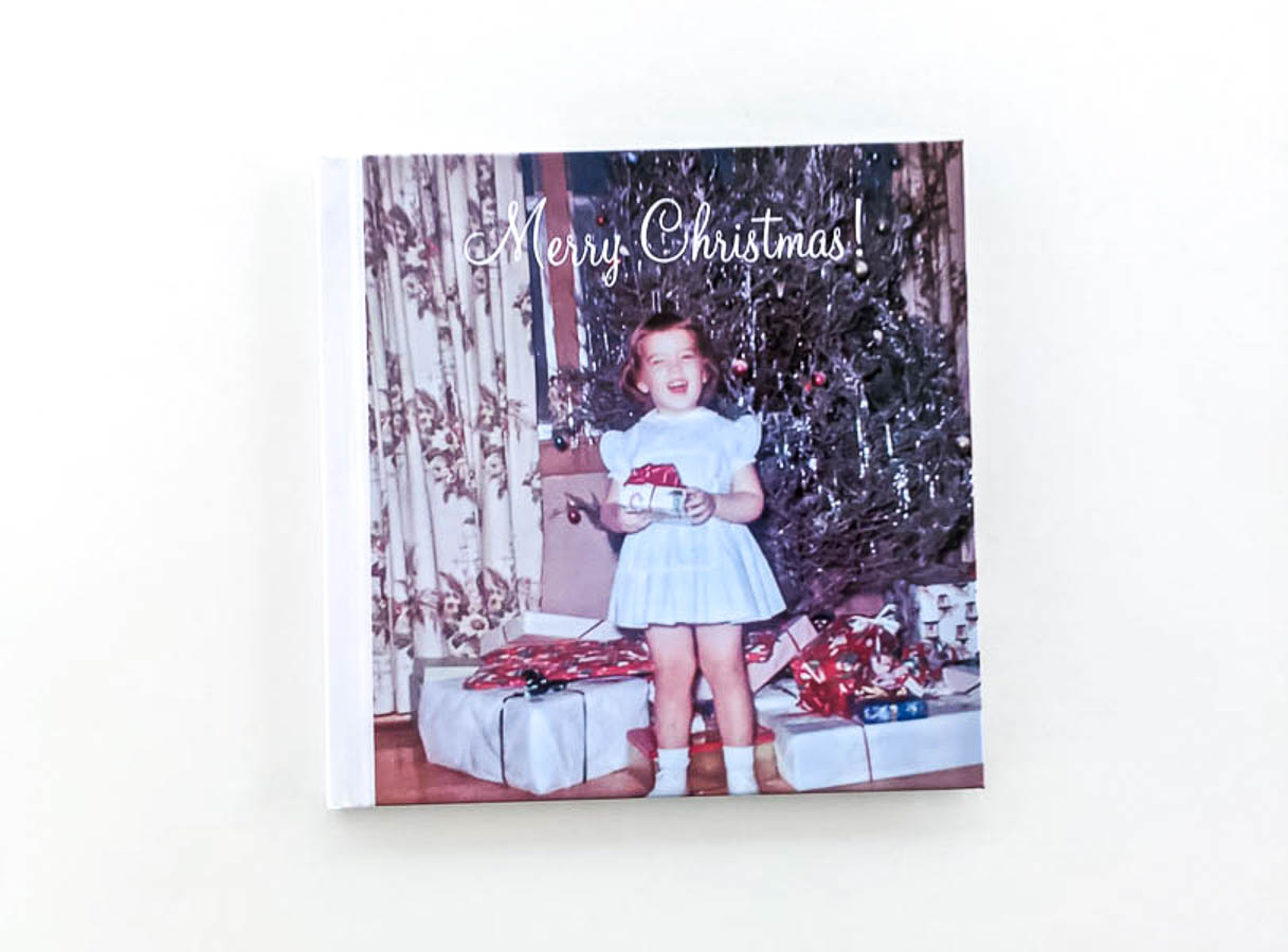 cover of photo book with little girl standing in front of Christmas tree in the 1950s with the text Merry Christmas in script.