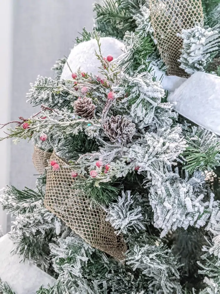 close up of Christmas tree with pinecones and berries on a branch sticking out.