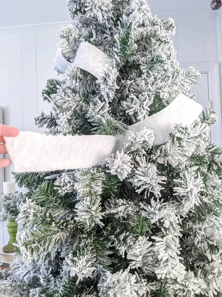 hand holding end of ribbon while forming two tufts of ribbon from Christmas tree.