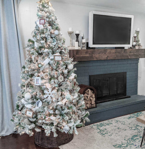 Decorated Christmas tree next to blue brick fireplace with wood mantel.