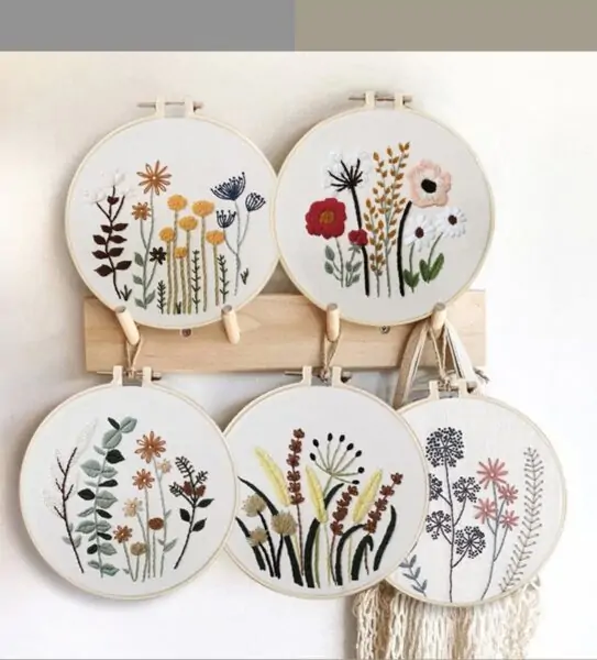 five embroidery hoops with different embroidered flower designs inside.