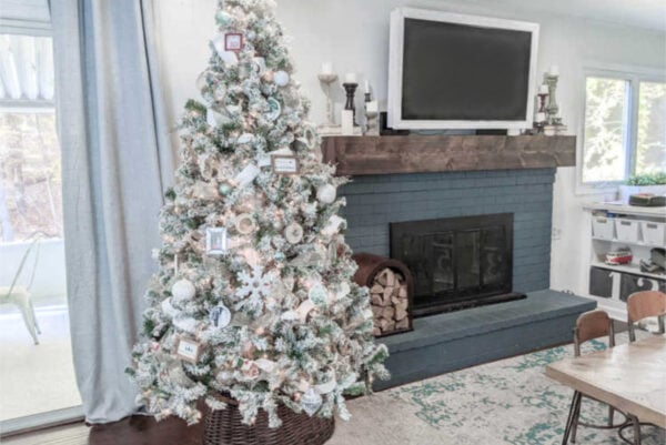 Christmas tree decorated next to blue brick fireplace.