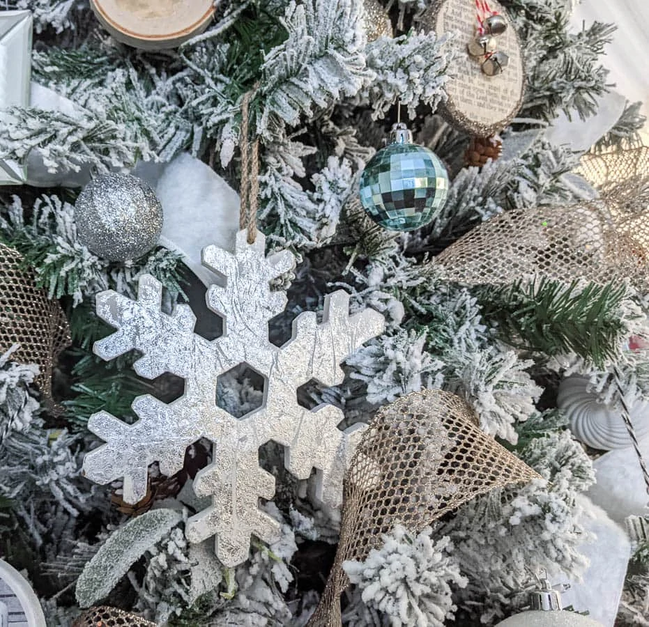 Close up of Christmas tree showing a large snowflake ornament next to some small ball ornaments.