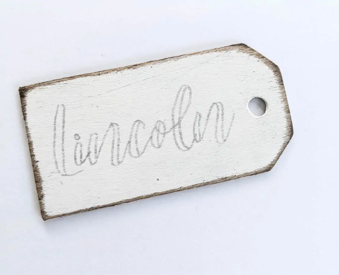 Painted wood stocking name tag with pencil outline of name.