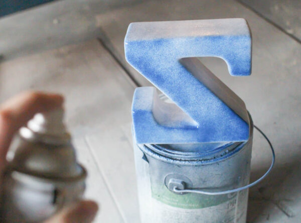painting a bookend with a thin first coat of spray paint.