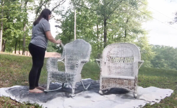 painting wicker chairs outside with spray paint.