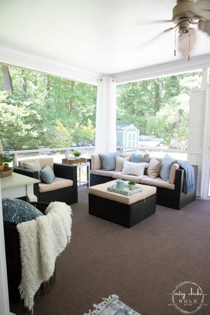 large screened in porch with wicker style furniture.