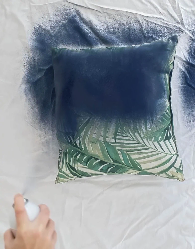 painting a pillow with outdoor fabric spray paint.