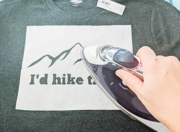 ironing a freezer paper stencil that says I'd hike that onto a thermal shirt.