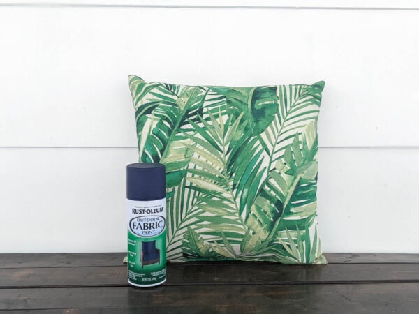 outdoor pillow with a green leaf pattern next to a can of Rustoleum outdoor fabric paint.