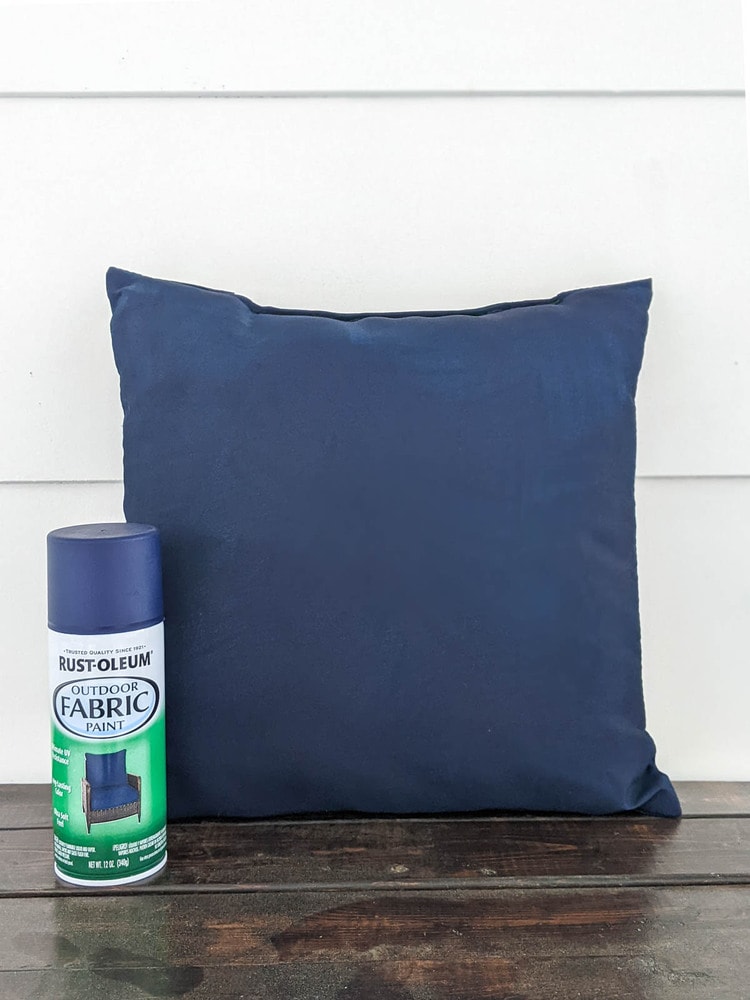 pillow painted with outdoor fabric spray paint next to a can of navy outdoor fabric spray paint.