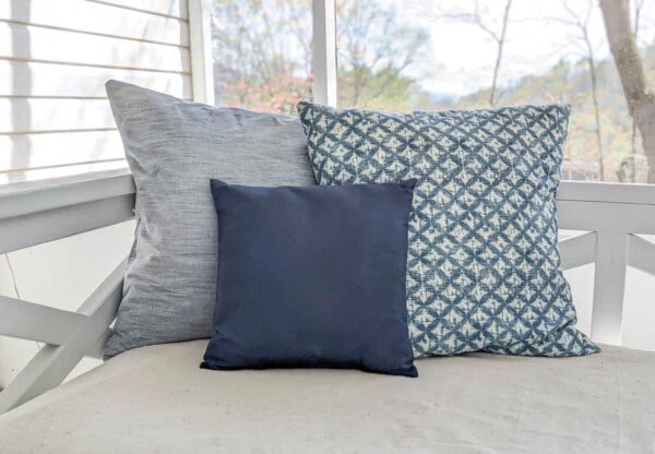 navy pillow painted with outdoor fabric paint next two two other pillows on porch daybed.