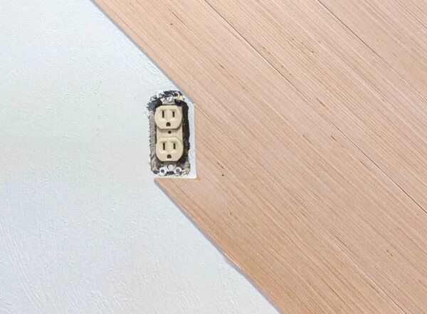 Cutting wood planks to fit around an electrical outlet.