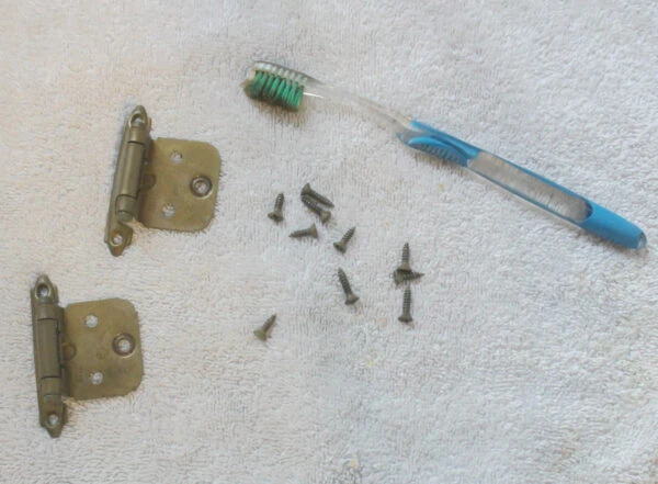 cleaning old hinges with a toothbrush.