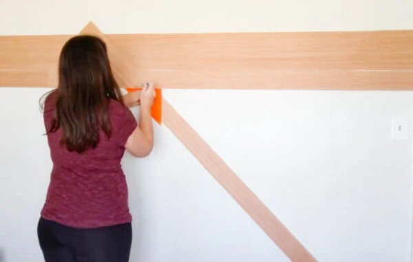 Using a speed square to mark where one end of the wood needs to be cut.