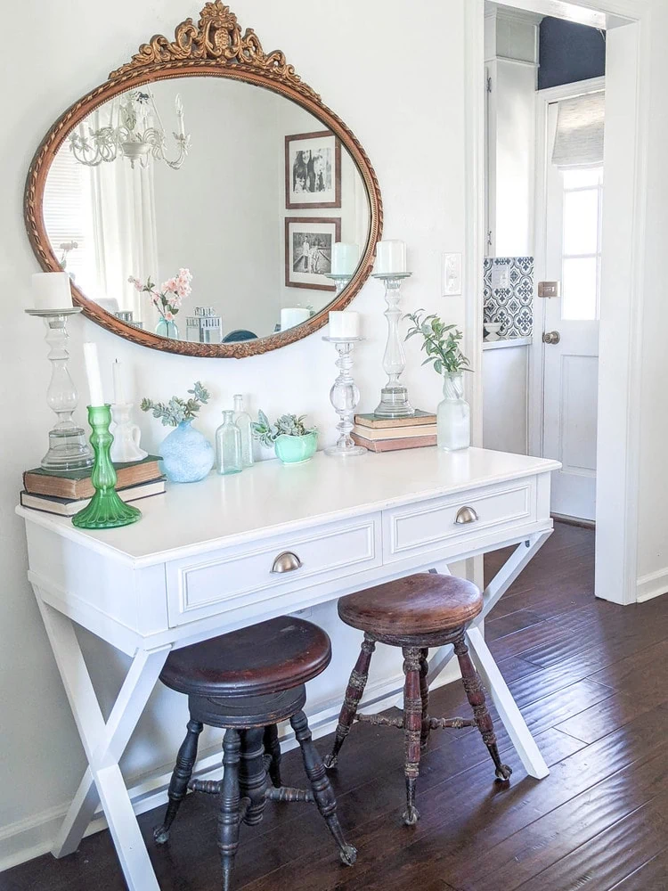 white table with gold oval mirror in dining room.