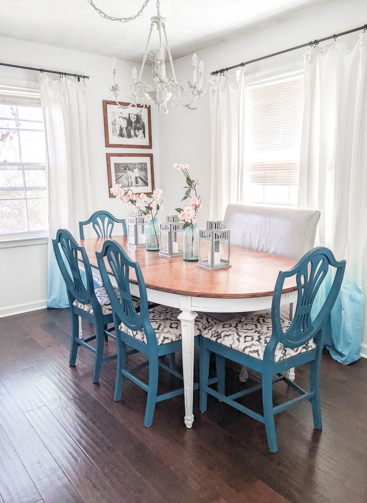 white and wood dining table with blue chairs and gray leather bench.