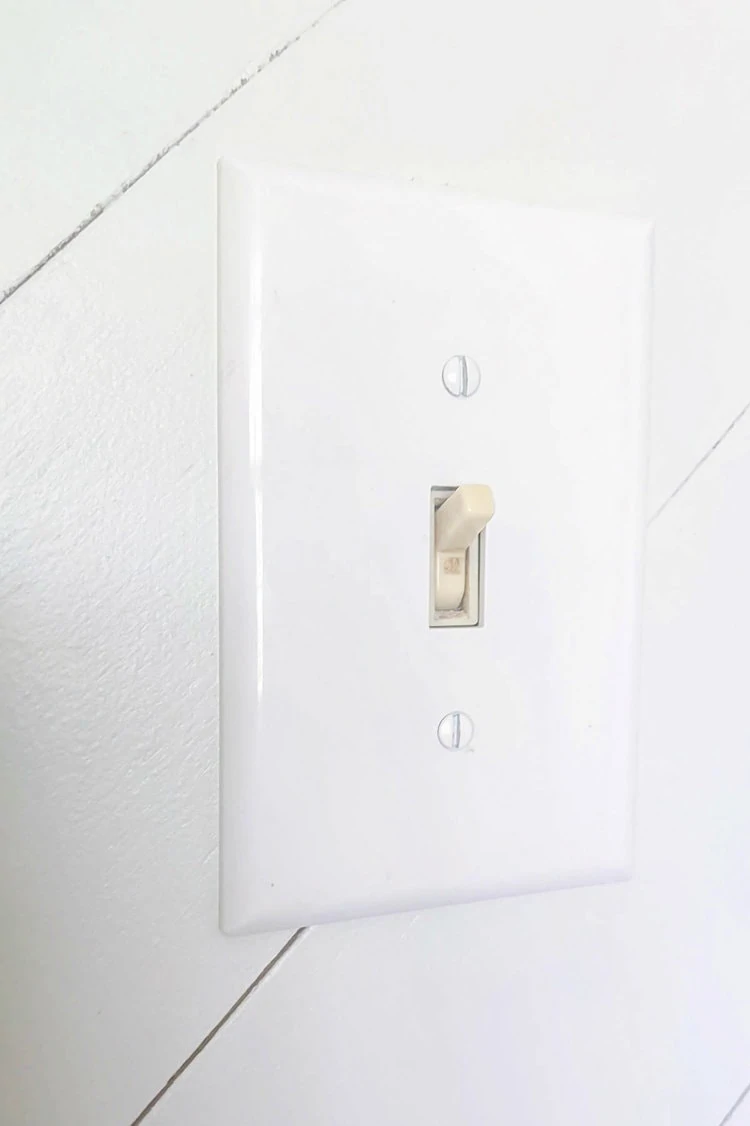 beige light switch with white wall plate.