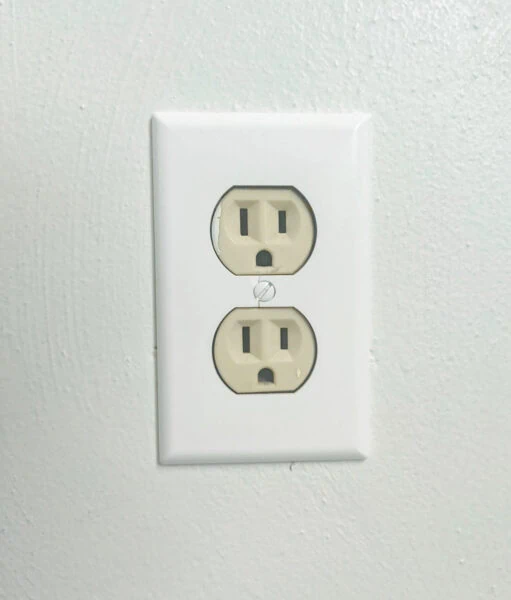 beige electrical outlet with white faceplate.
