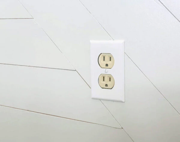 beige outlet with white wall plate against white wood wall.
