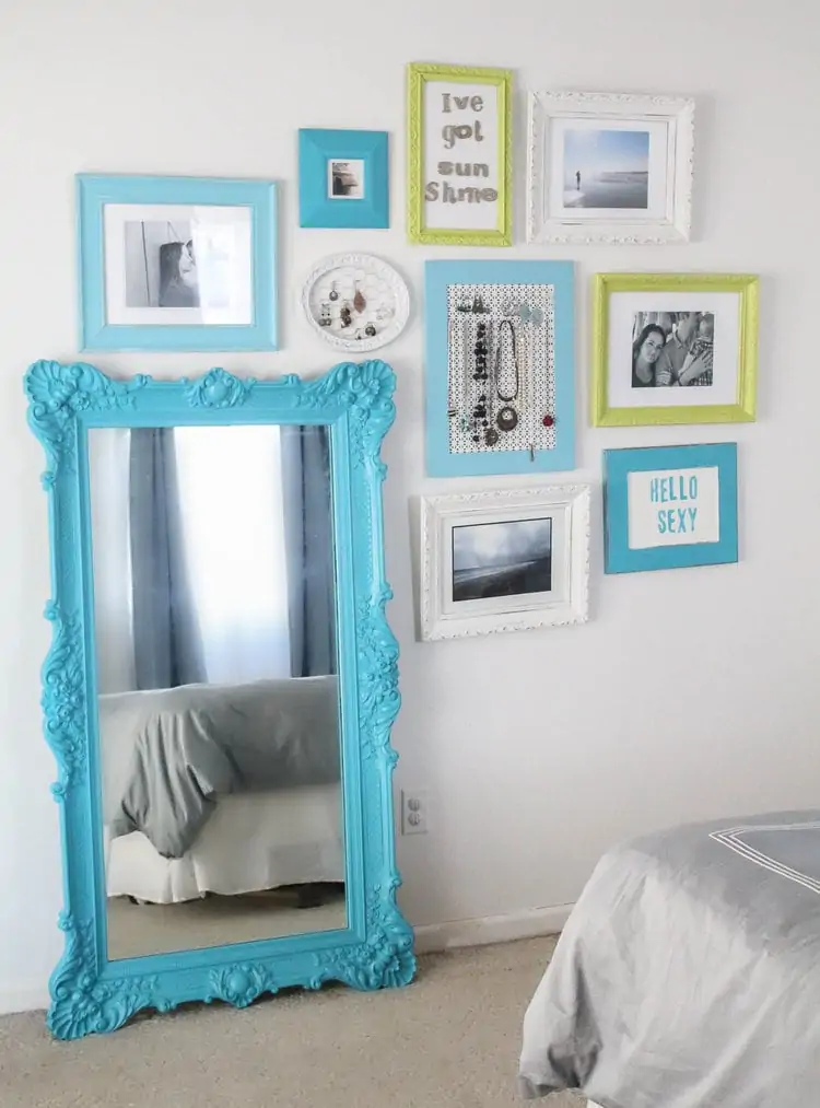 finished gallery wall with framed art hanging around a leaning mirror.