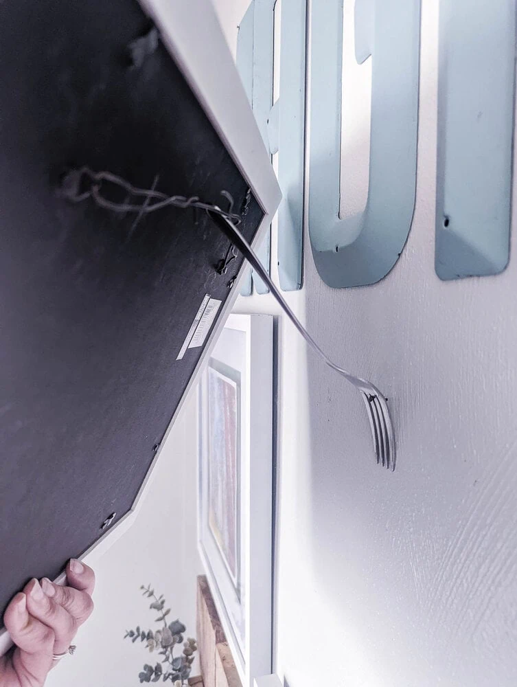 sliding a picture frame with a wire on the back over a fork.