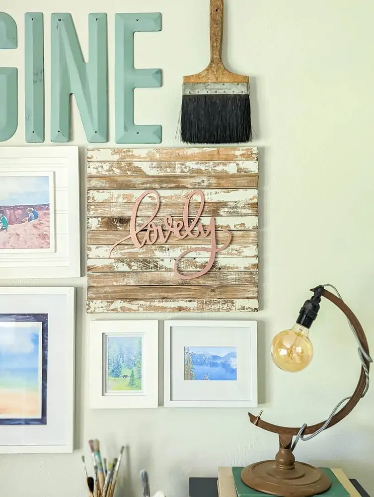 weathered wood background with rose gold letters spelling lovely in center of gallery wall.