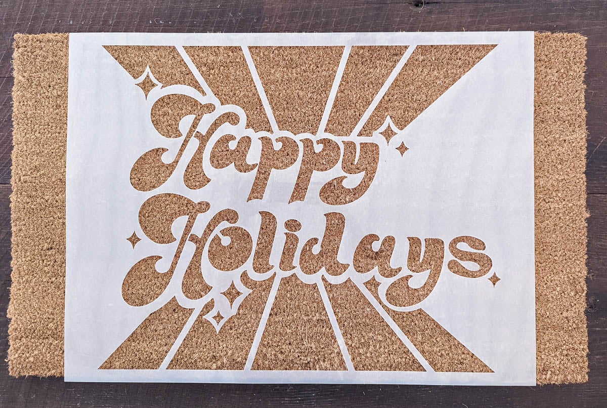 happy holidays stencil on top of blank doormat.