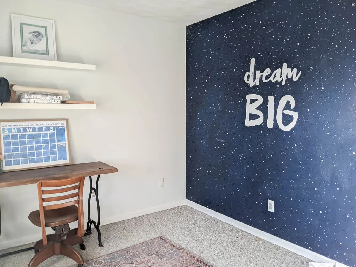 Dream Big mural with crib and dresser gone and a desk and desk chair in their place.