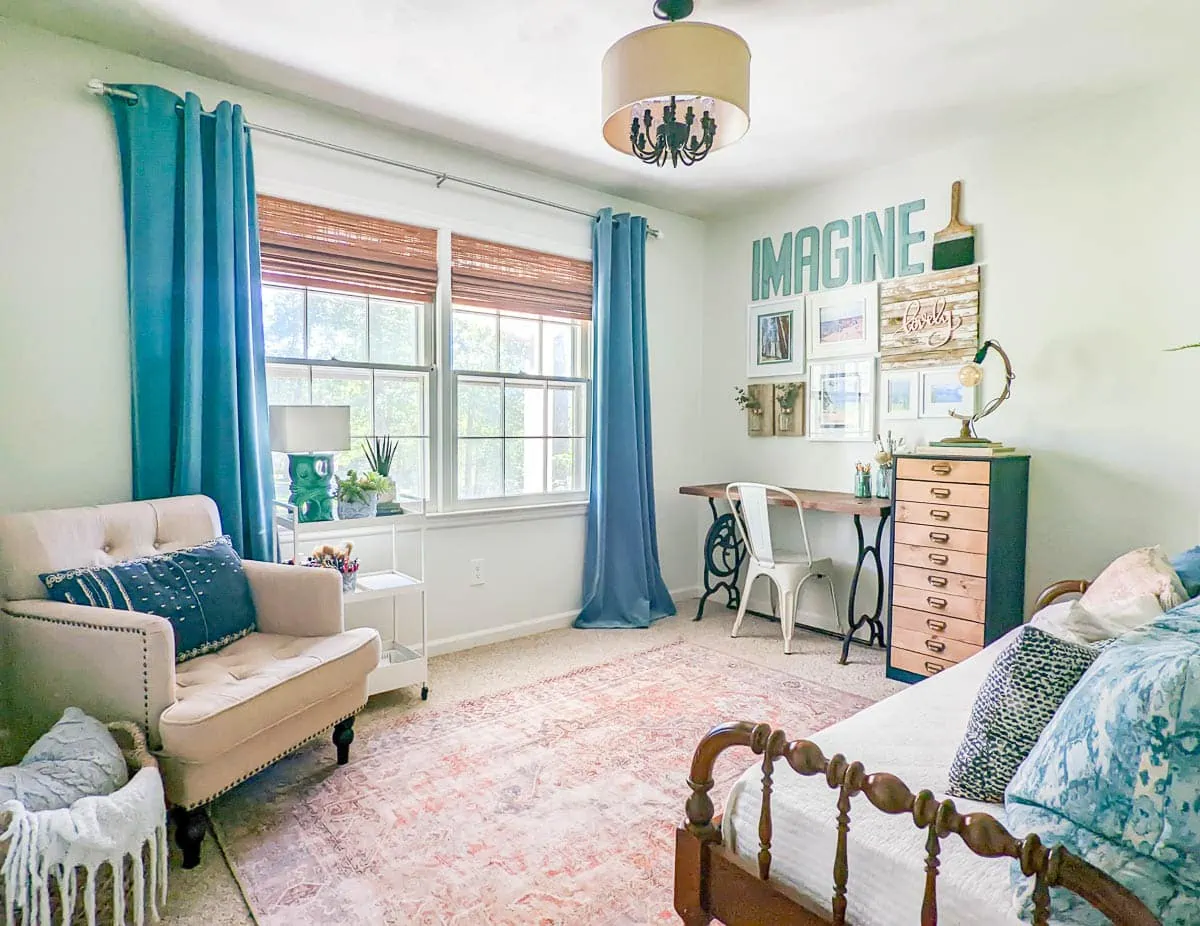 wide view of office including windows with bamboo window shades and teal velvet curtains.