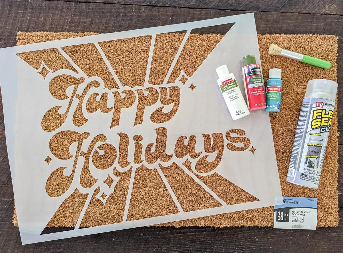 materials for painting a doormat - blank doormat, happy holidays stencil, outdoor craft paints, stencil brush, and flex seal clear spray.