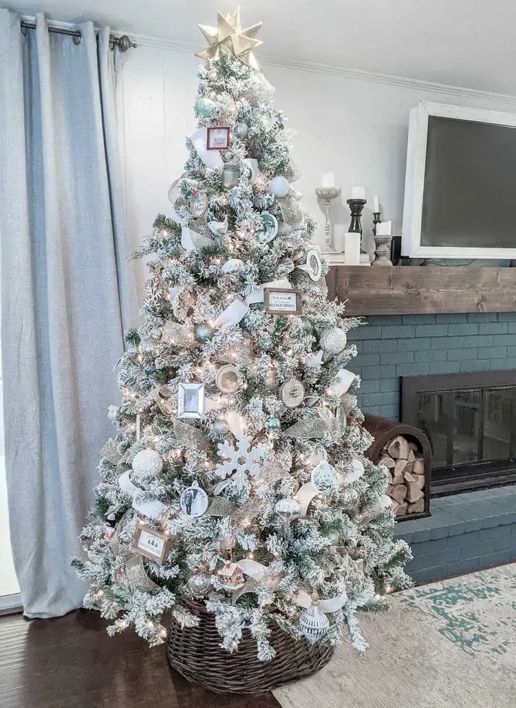 Christmas tree decorated with gold and white ribbon, neutral ornaments, and gold star.