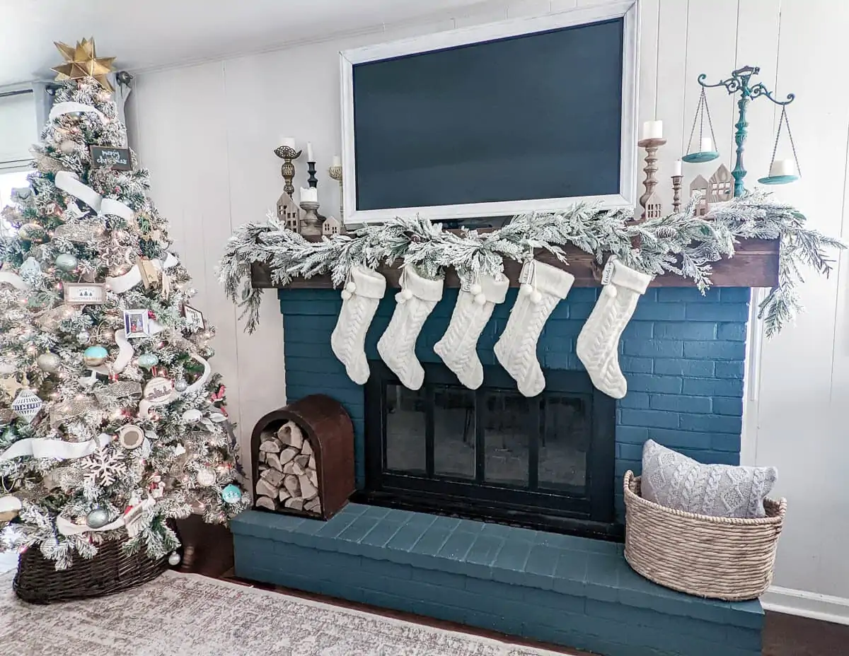 flocked Christmas tree next to fireplace with flocked garland and stockings.