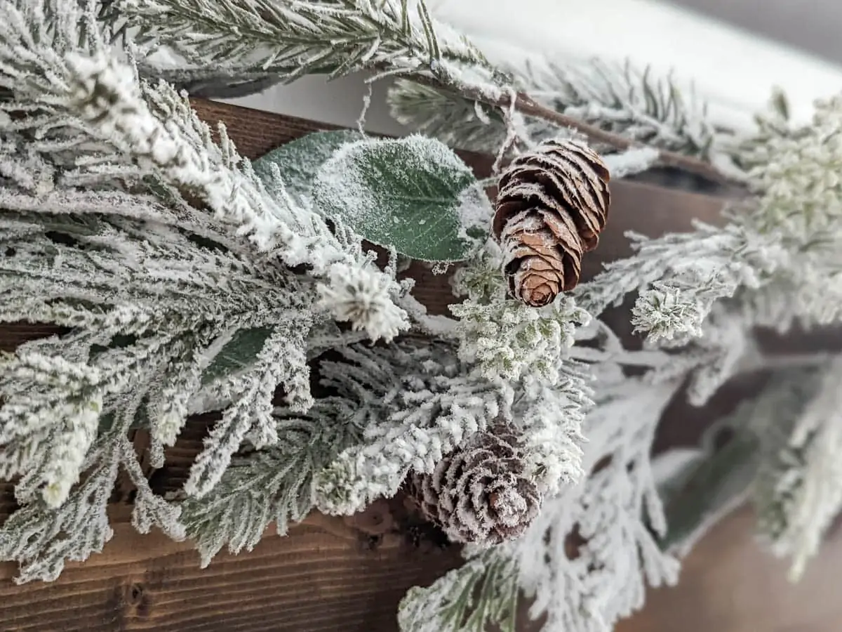 flocked garland with pinecones hanging on fireplace.