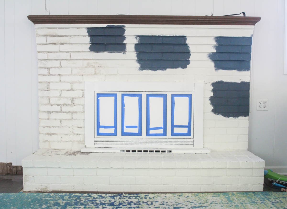 various navy paint samples painted on brick fireplace.
