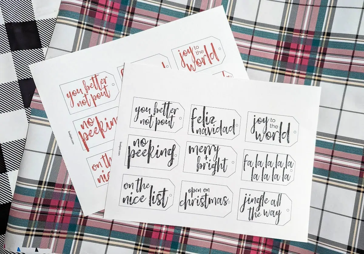 two sheets of printed gift tags on top of plaid wrapping paper.