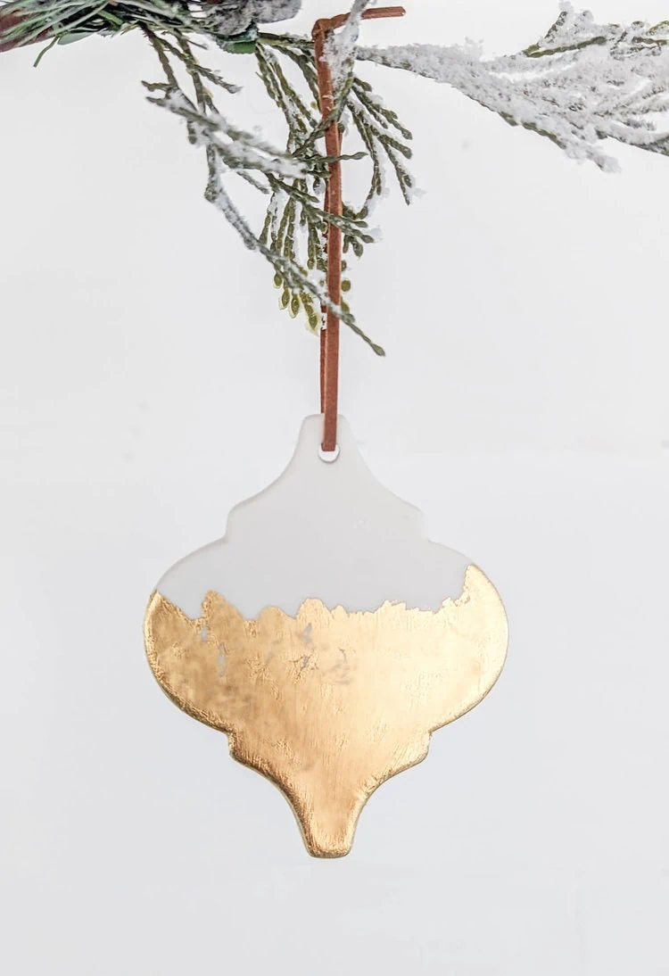 ceramic tile ornament with gold leaf on lower half.