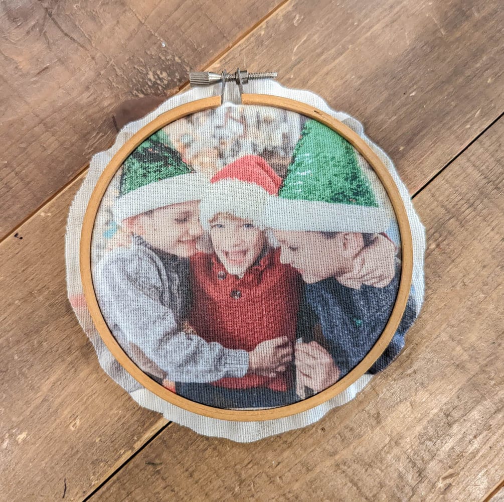 photo of three boys in embroidery hoop with a small border of extra fabric sticking out the back.