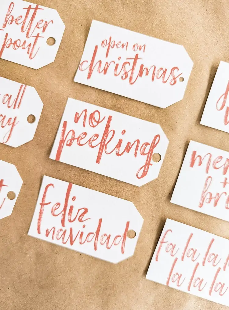 free printable gift tags with red script that read open on christmas, no peeking, and feliz navidad.