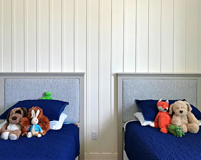 Cream board and batten walls between two twin beds.