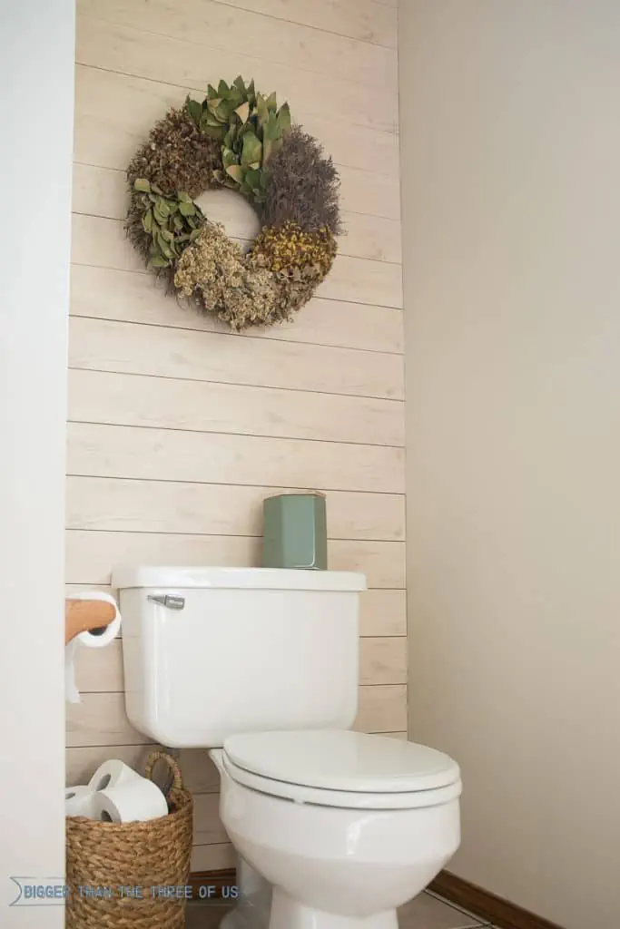 Wood accent wall behind toilet using light wood wall planks.