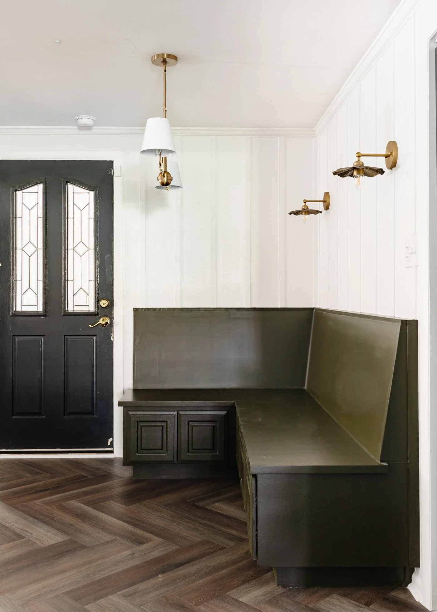 White board and batten wall made with wood lattice next to dark built-in banquette.